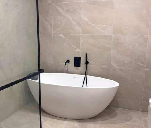 Moderne badkuip met beige tegels