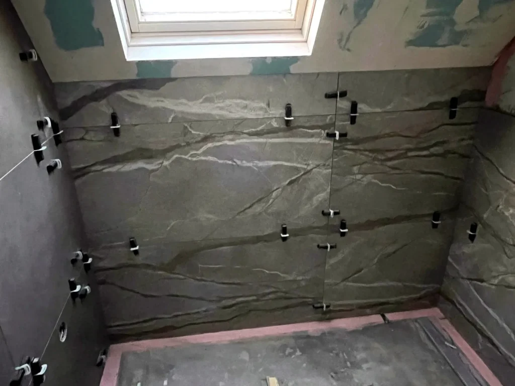 Koper Marmer — badkamer tegelwerk met grootformaat marmerlook wandtegels onder dakraam