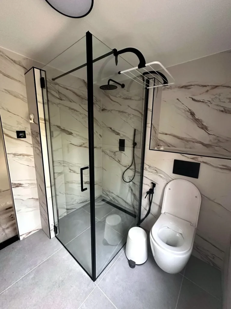 Marble Noir — badkamer met marmerlook tegels en hoekdouche met zwarte glazen wand